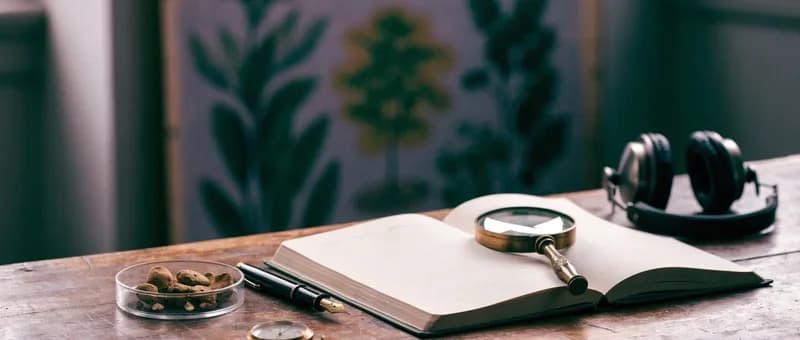 Cuaderno de investigación lupa auriculares y setas secas en una placa de Petri sobre mesa de madera